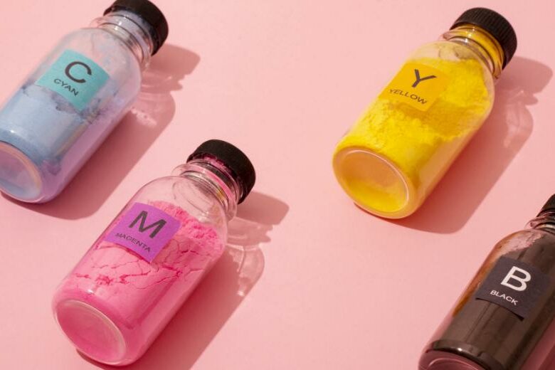 best printers for artists and graphic designers - image of still-life CMYK color toners in bottles, placed in lied down position on a light pink background.