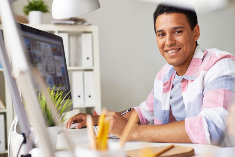 aesthetic work desk ideas - Smiling student in a pastel pink & blue checked shirt on a work desk