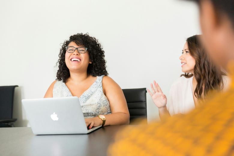 woman sitting in front of the laptop, smiling while working with her clients